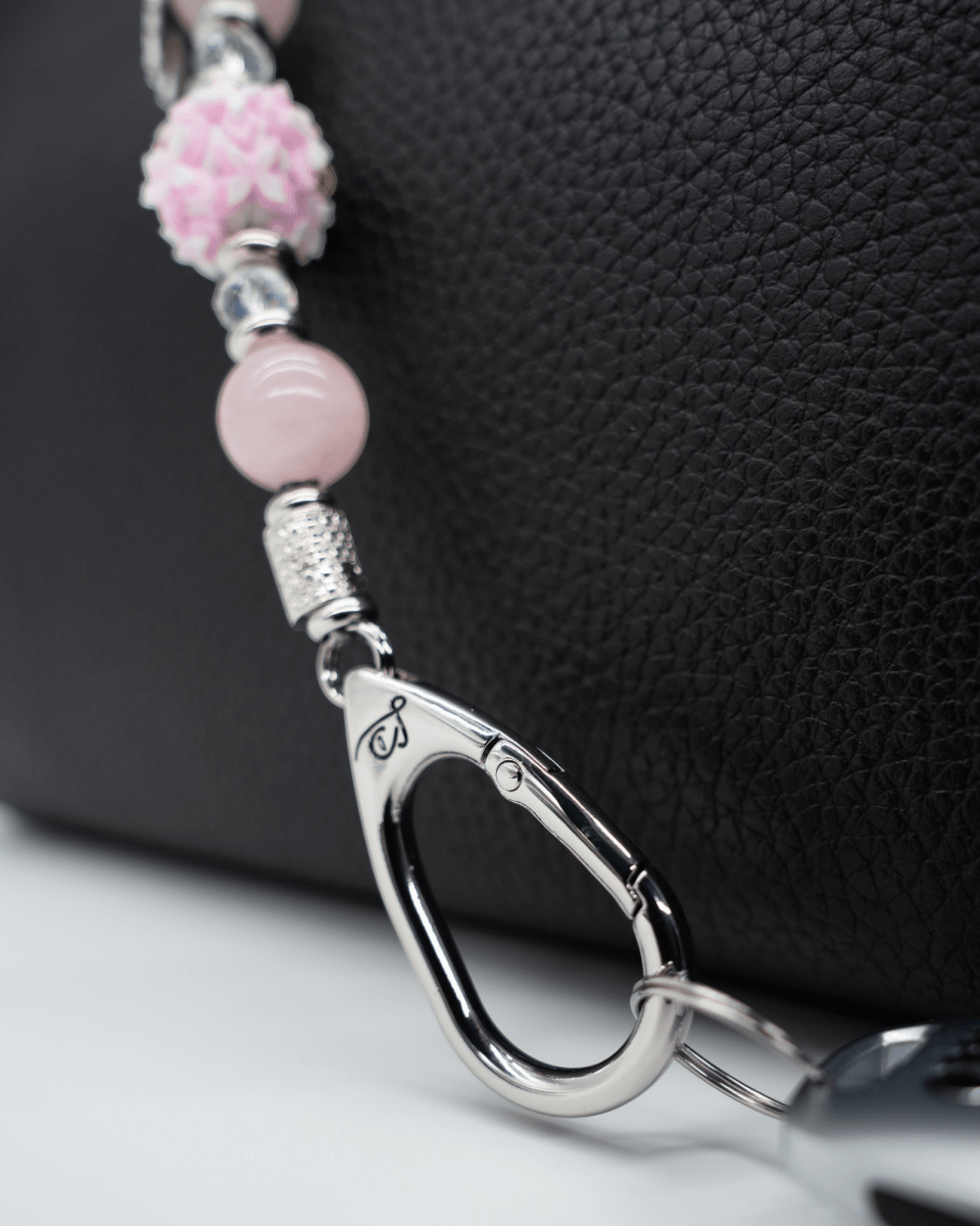 LD Keyfinder Hope Blooms-Mini featuring rose quartz beads, iridescent glass, and a platinum-plated clasp on a handbag.