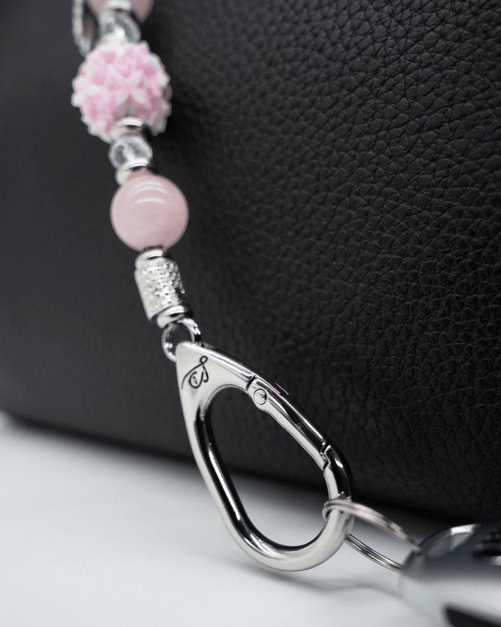 LD Keyfinder Hope Blooms-Mini featuring rose quartz beads, iridescent glass, and a platinum-plated clasp on a handbag.