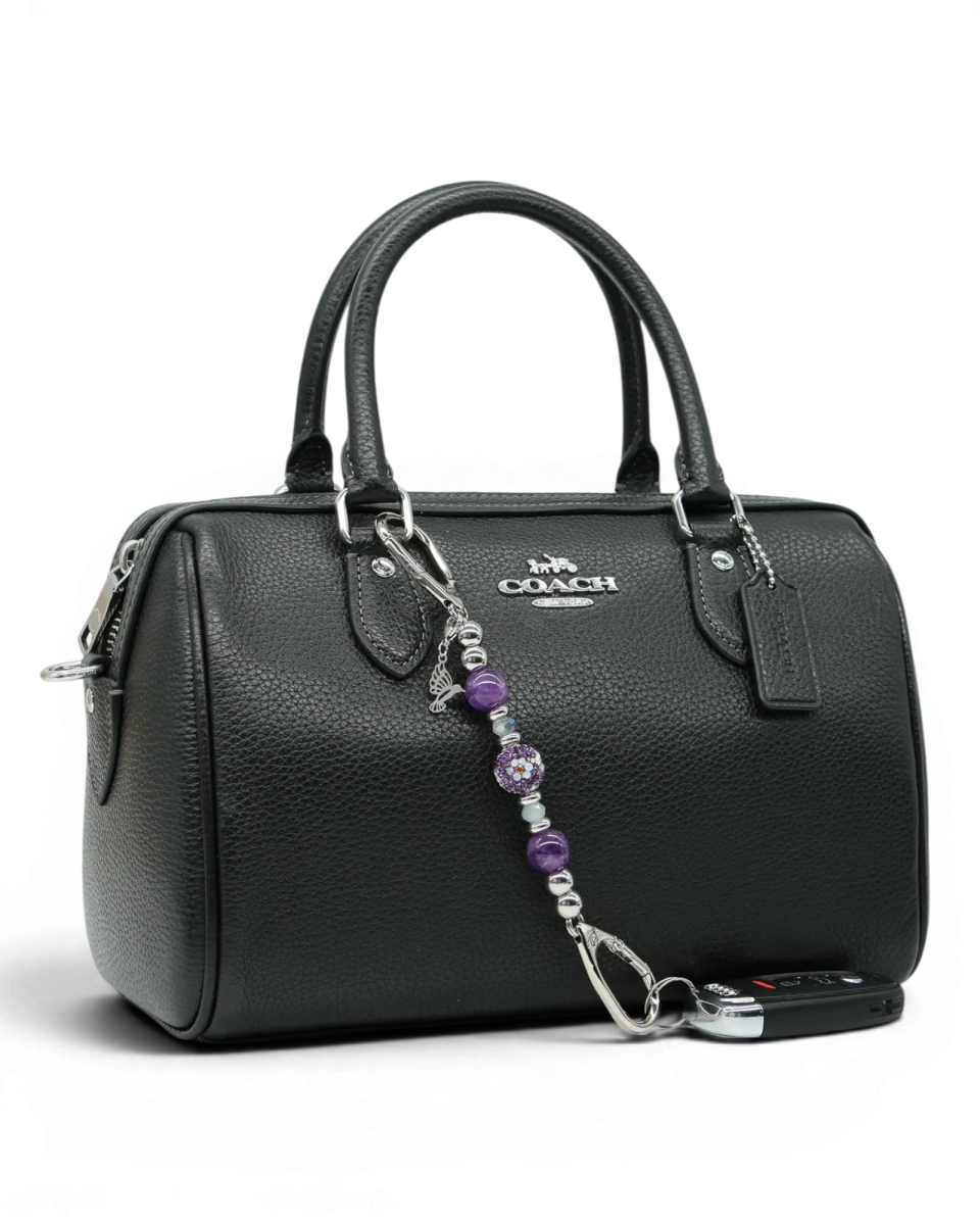 LD Keyfinder Hummingbird Dream Mini charm with purple amethyst beads, Austrian crystals, and silver hummingbird charm on a black handbag.