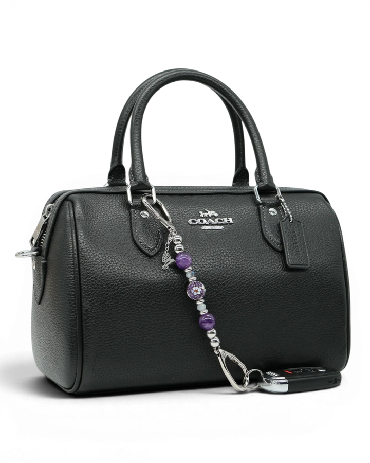 LD Keyfinder Hummingbird Dream Mini charm with purple amethyst beads, Austrian crystals, and silver hummingbird charm on a black handbag.