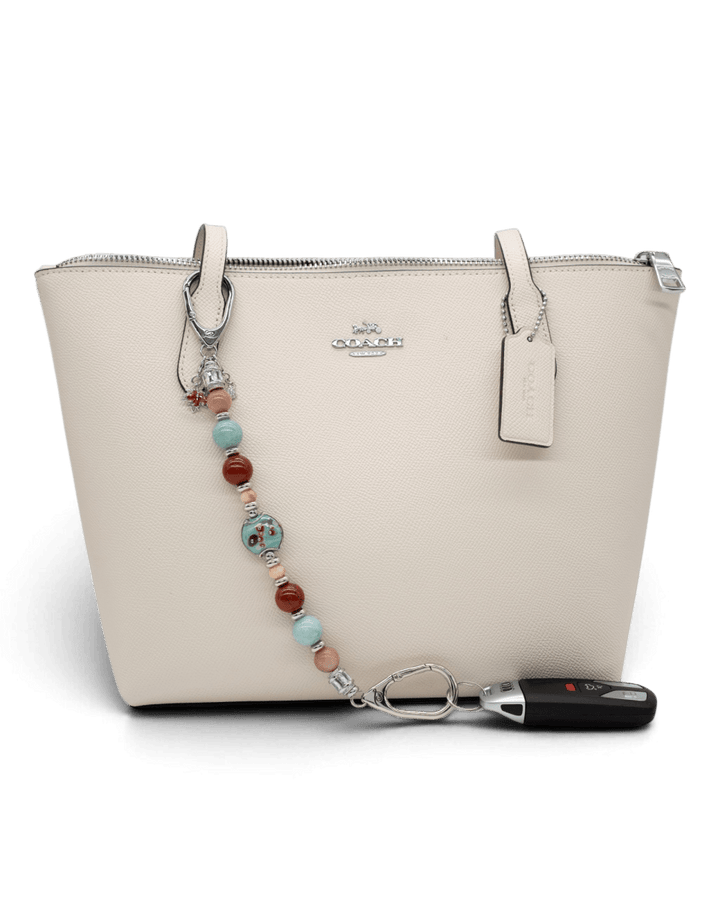 LD Keyfinder Maple Majesty beaded accessory attached to a cream leather handbag with a car key fob.