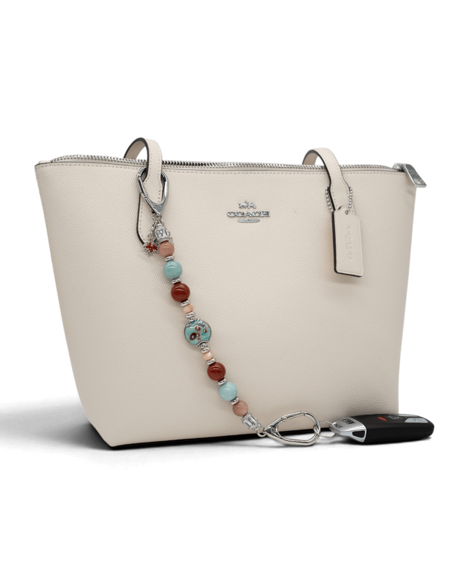 LD Keyfinder Maple Majesty beaded accessory with artisan glass, jasper, and jade beads attached to a cream handbag.