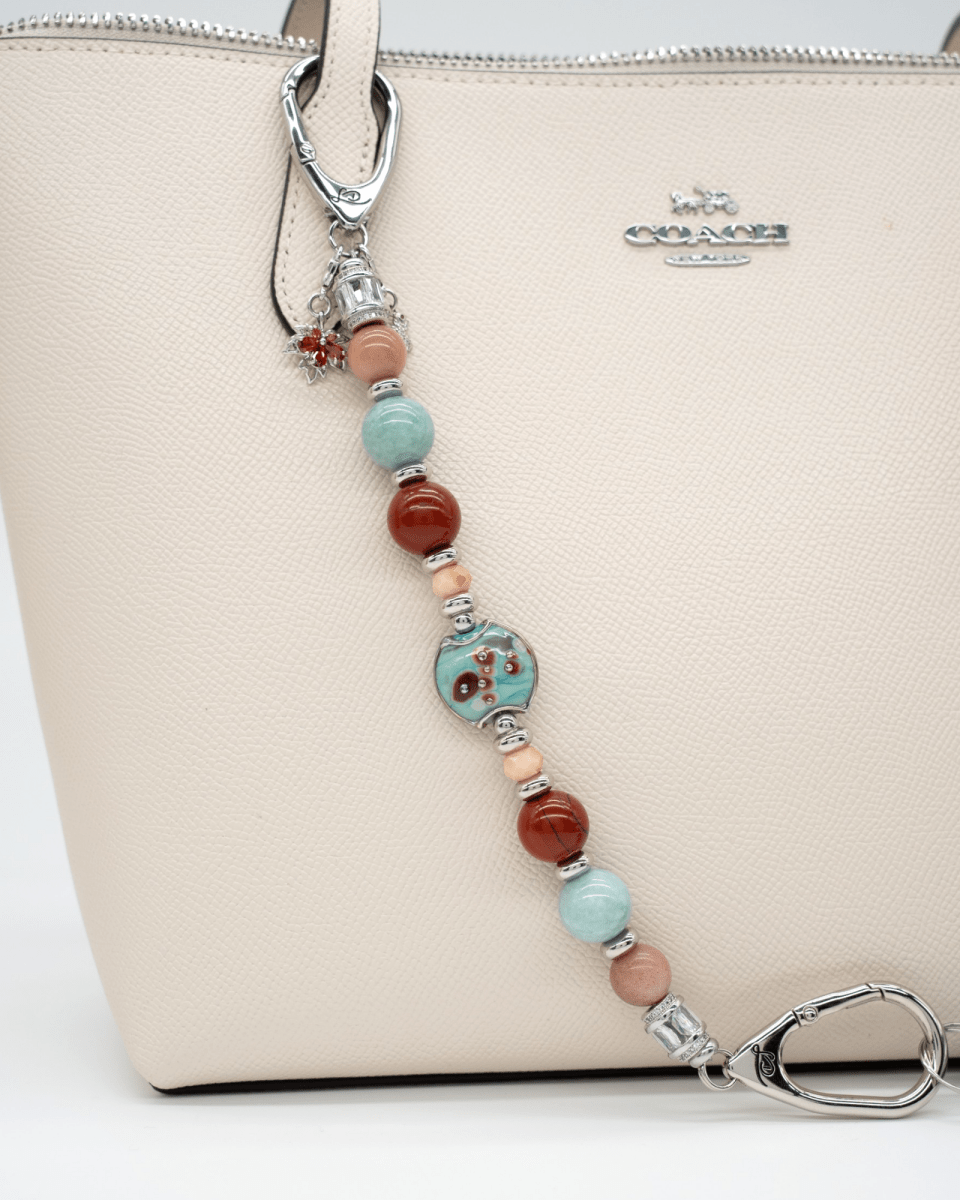 LD Keyfinder Maple Majesty accessory featuring red jasper, aqua jade, and artisan glass beads on a cream leather tote.