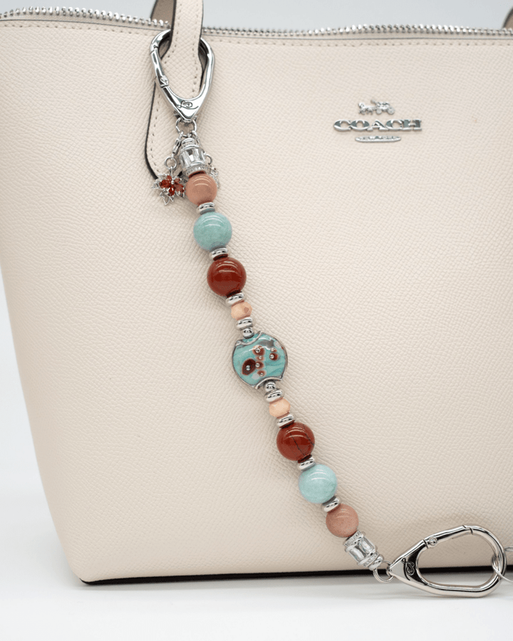 LD Keyfinder Maple Majesty accessory featuring red jasper, aqua jade, and artisan glass beads on a cream leather tote.