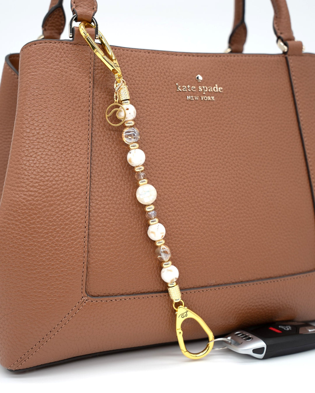 LD Keyfinder Mediterranean Glow beaded key holder with Mother of Pearl, ivory shells, and gold charms on a brown bag