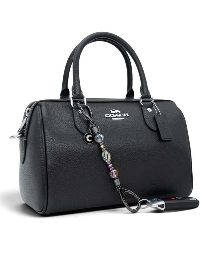 LD Keyfinder Midnight Aurora-Mini beaded charm with abalone and rainbow crystals attached to a black leather handbag