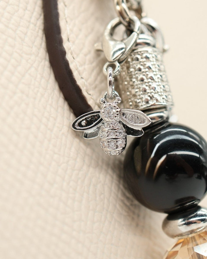 LD Keyfinder Midnight Hive bracelet with black obsidian beads, crystal bumblebee charm, and faceted golden bead.
