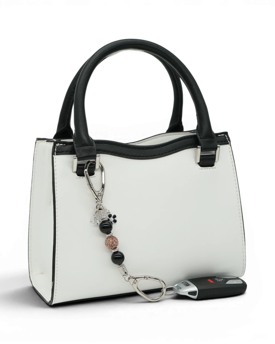 LD Keyfinder Midnight Hive Mini keychain with black obsidian beads, crystal accents, and bumblebee charm attached to a white handbag.