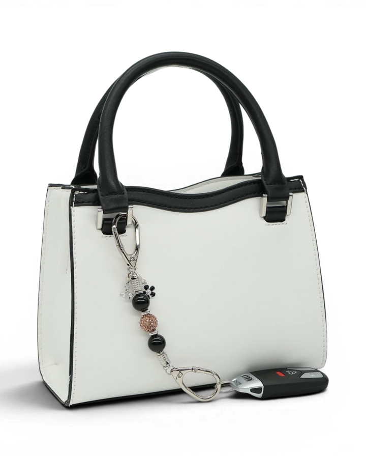 LD Keyfinder Midnight Hive Mini keychain with black obsidian beads, crystal accents, and bumblebee charm attached to a white handbag.
