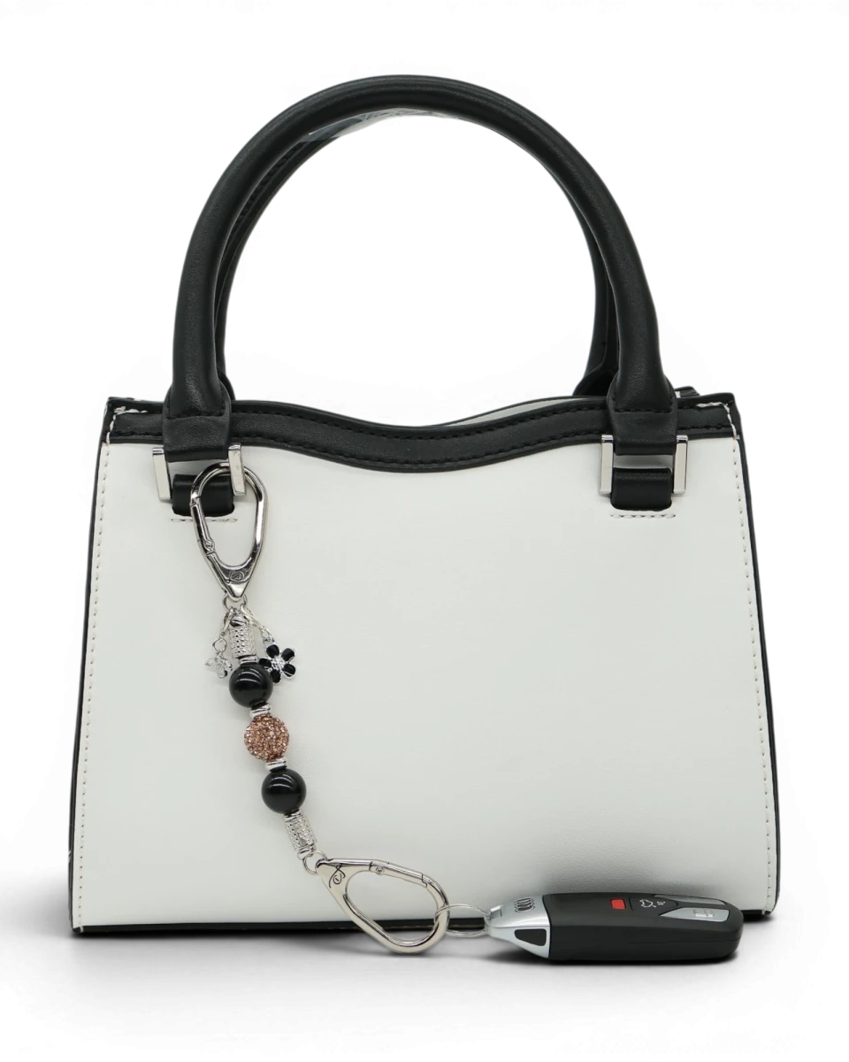 LD Keyfinder Midnight Hive Mini keychain with black obsidian beads, crystal charm, bumblebee, and flower charm attached to a white handbag.