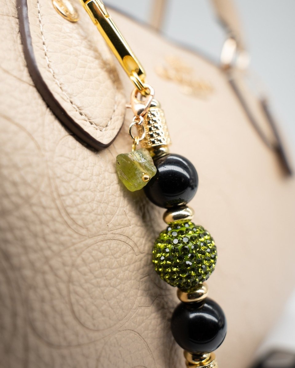 LD Keyfinder Midnight Peridot-Mini featuring black obsidian, green crystal beads, and gold accents on a beige bag