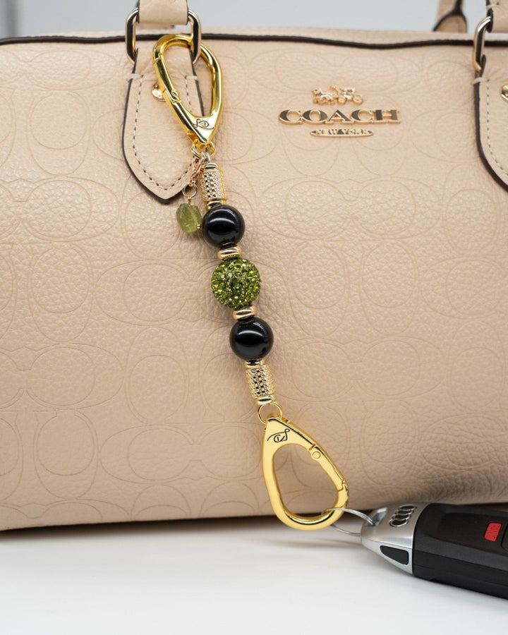 LD Keyfinder Midnight Peridot-Mini beaded keychain with black obsidian, green crystals, and gold accents on a handbag