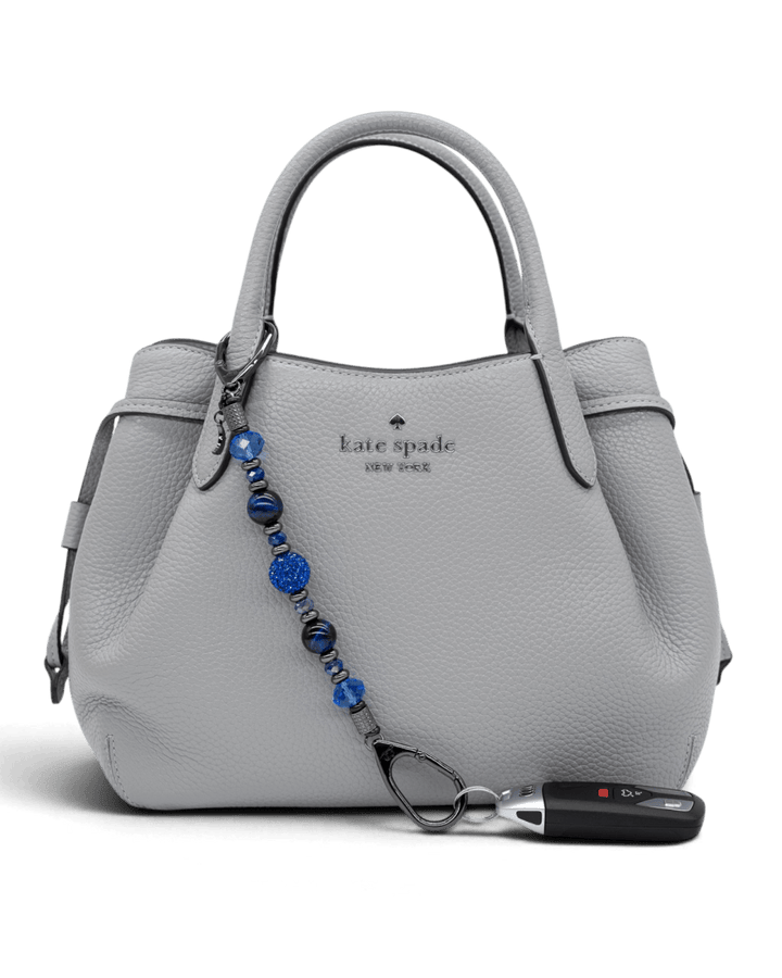 LD Keyfinder Midnight Sapphire beaded accessory attached to a grey leather handbag with a car key fob