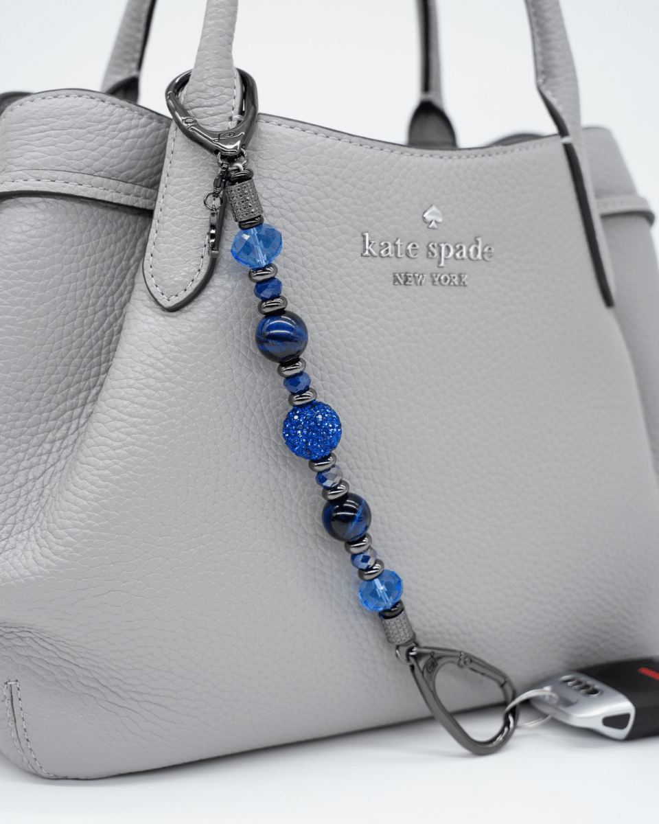 LD Keyfinder Midnight Sapphire beaded keychain with blue tiger eye, Austrian crystals, and a moon charm on a handbag.