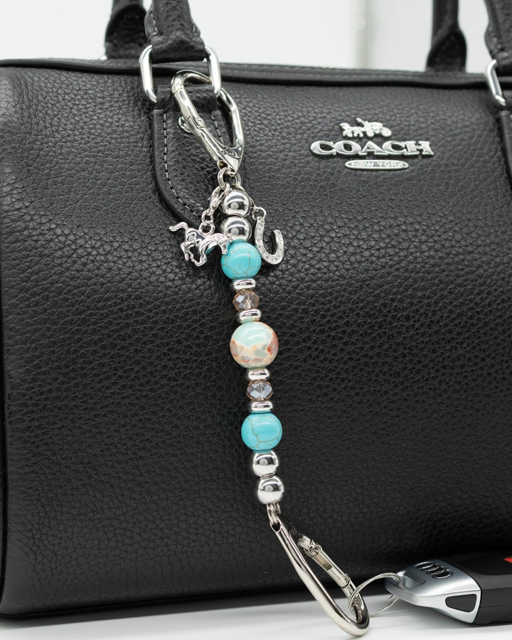 LD Keyfinder Mini Cowgirl Dreams beaded keychain with turquoise, jasper, and horse charms clipped to a black handbag.