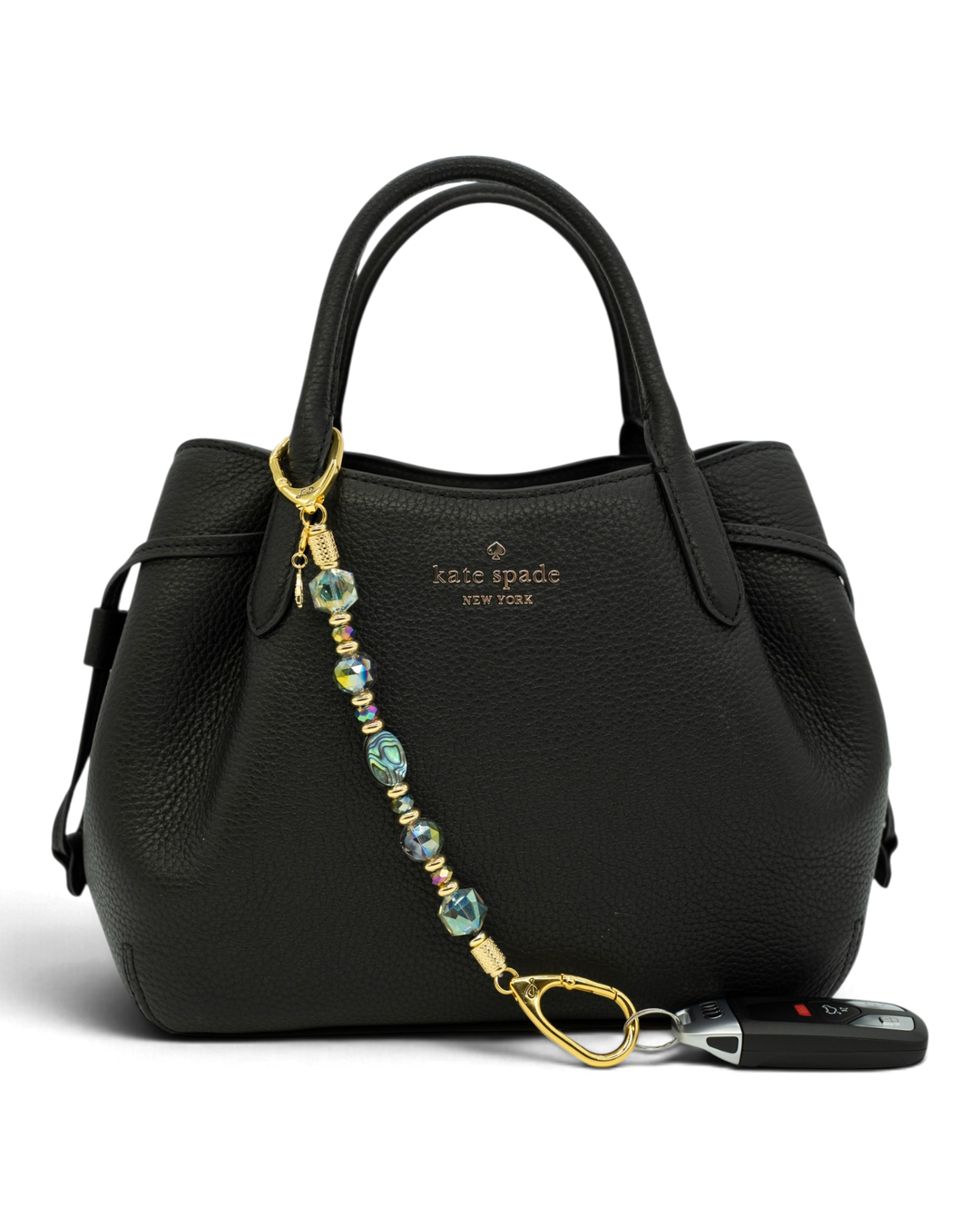 LD Keyfinder Northern Lights beaded keychain with abalone shell and rainbow crystals attached to a black leather bag