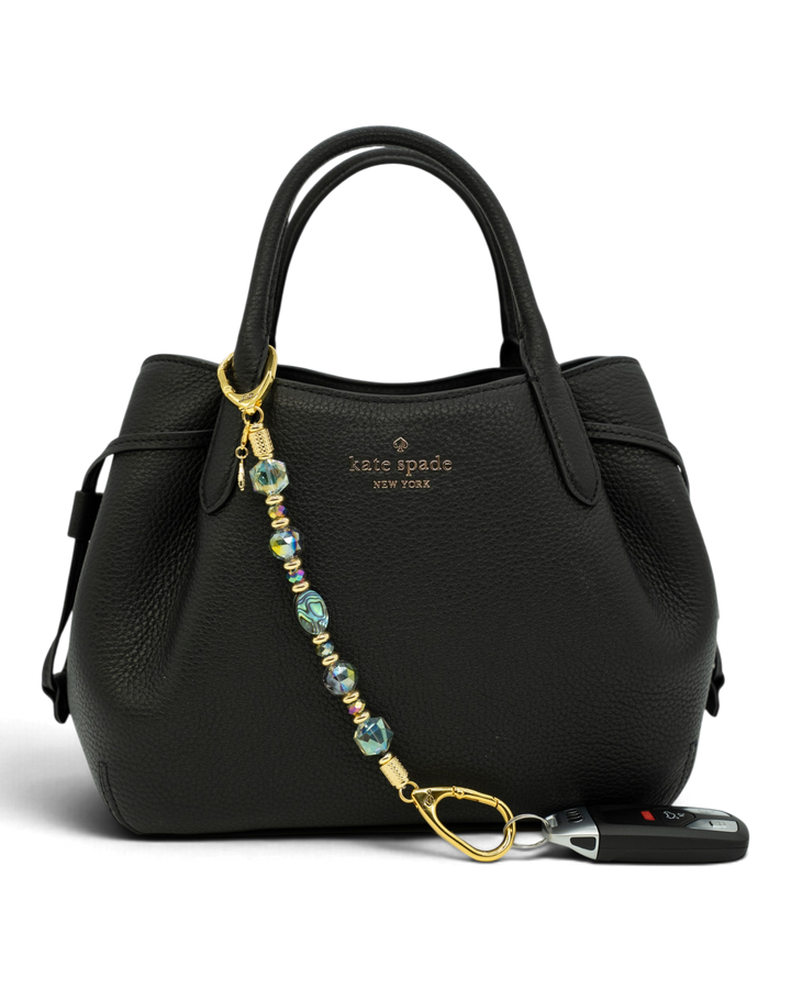 LD Keyfinder Northern Lights beaded keychain with abalone shell and rainbow crystals attached to a black leather bag
