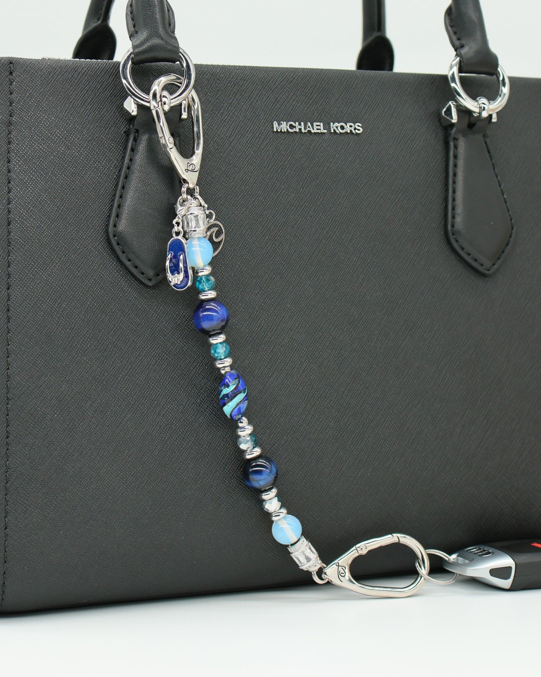 LD Keyfinder Ocean Mosaic beaded key chain with blue tiger eye, opalite, and artisan glass beads on a black handbag.