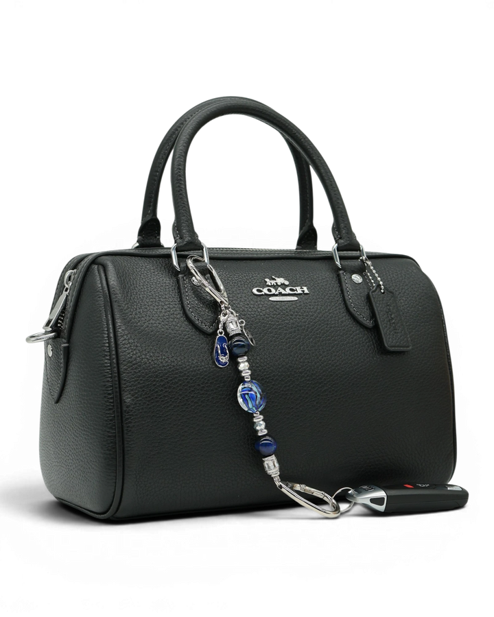 LD Keyfinder Ocean Mosaic Petite attached to a black leather handbag, featuring blue artisan glass and tiger eye beads.