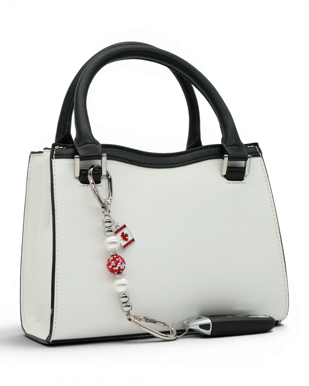 LD Keyfinder Oh Canada Shimmer Mini keychain with white pearls, red crystal bead, and Canada flag charm attached to a white handbag.