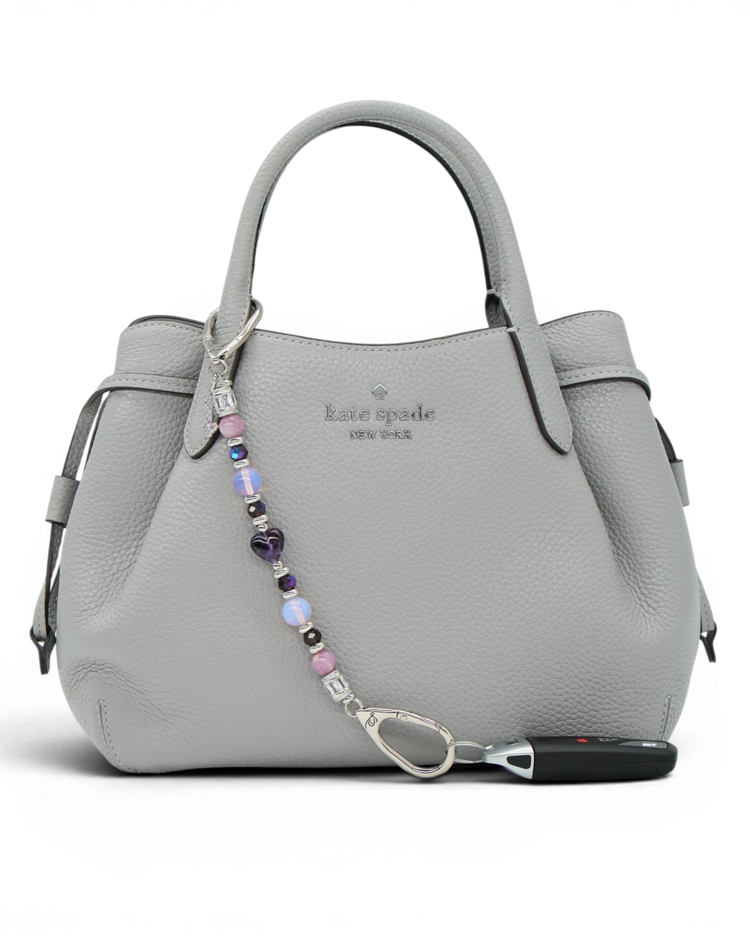 LD Keyfinder Orchid Flutter beaded accessory with lepidolite, opalite, and butterfly charm attached to a grey handbag.