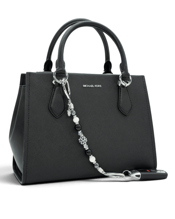 LD Keyfinder Owl That Glitters beaded accessory with obsidian, moonstone, and a sparkling owl charm on a black handbag