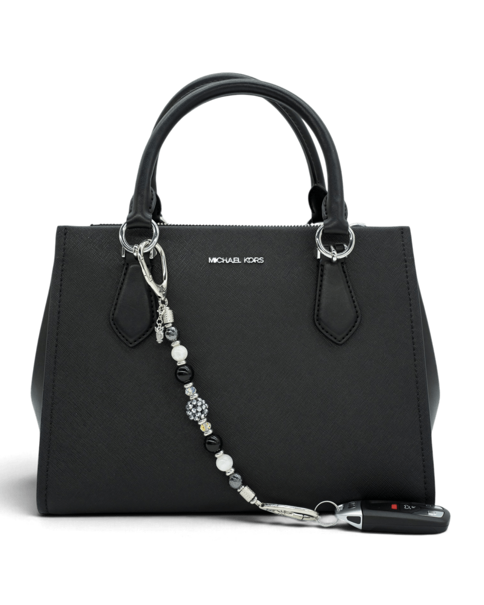 LD Keyfinder Owl That Glitters accessory featuring obsidian, moonstone, and a sparkling owl charm on a black handbag.