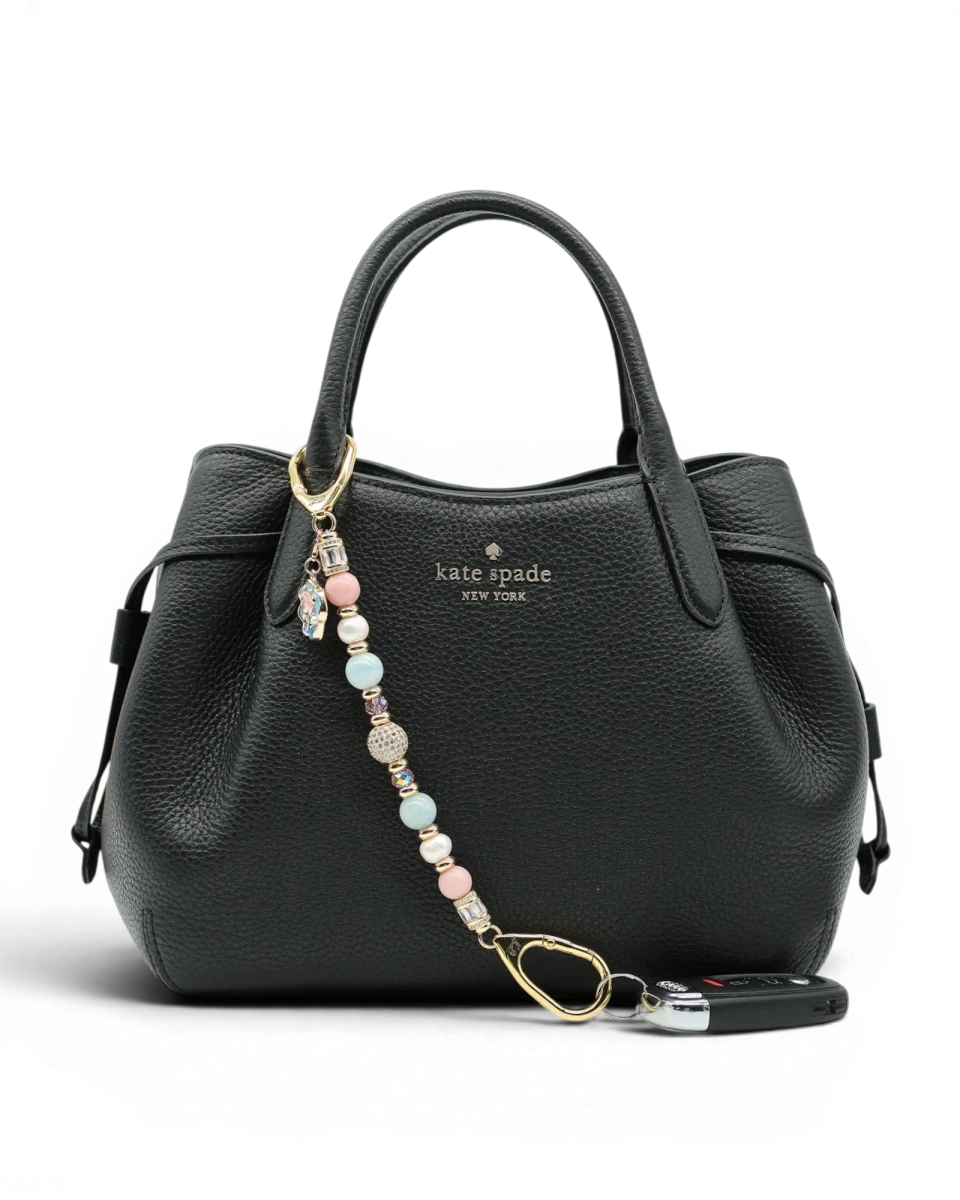 LD Keyfinder Pastel Garden charm with pink opal, freshwater pearls, aquamarine, and gold-plated beads on a black handbag.