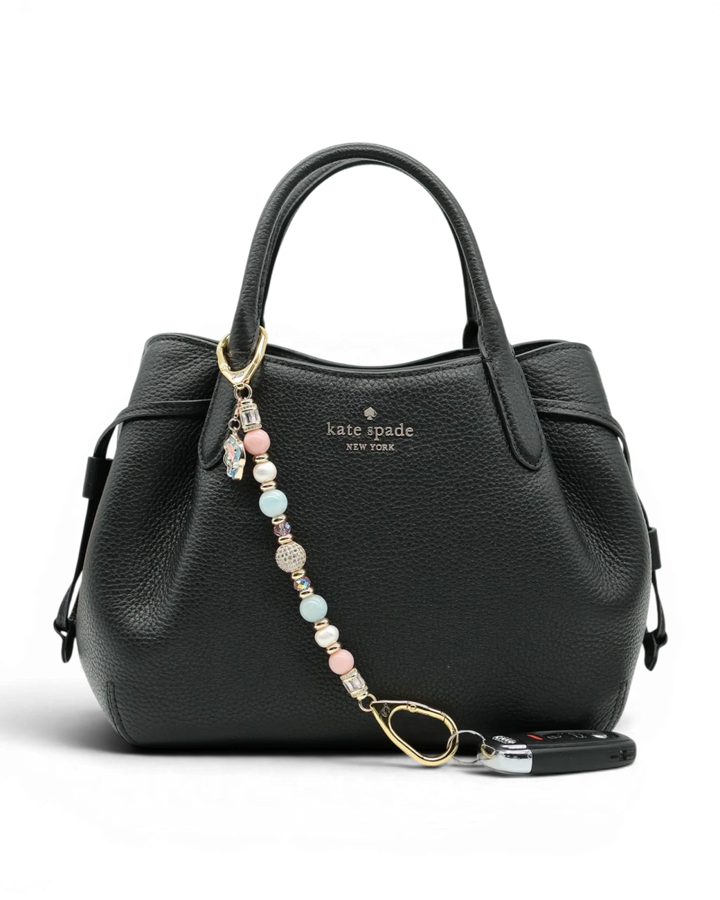 LD Keyfinder Pastel Garden charm with pink opal, freshwater pearls, aquamarine, and gold-plated beads on a black handbag.