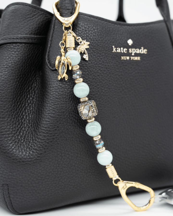 LD Keyfinder Paua Paradise beaded keychain with aqua jade, paua shell, turtle and palm tree charms on a black bag.