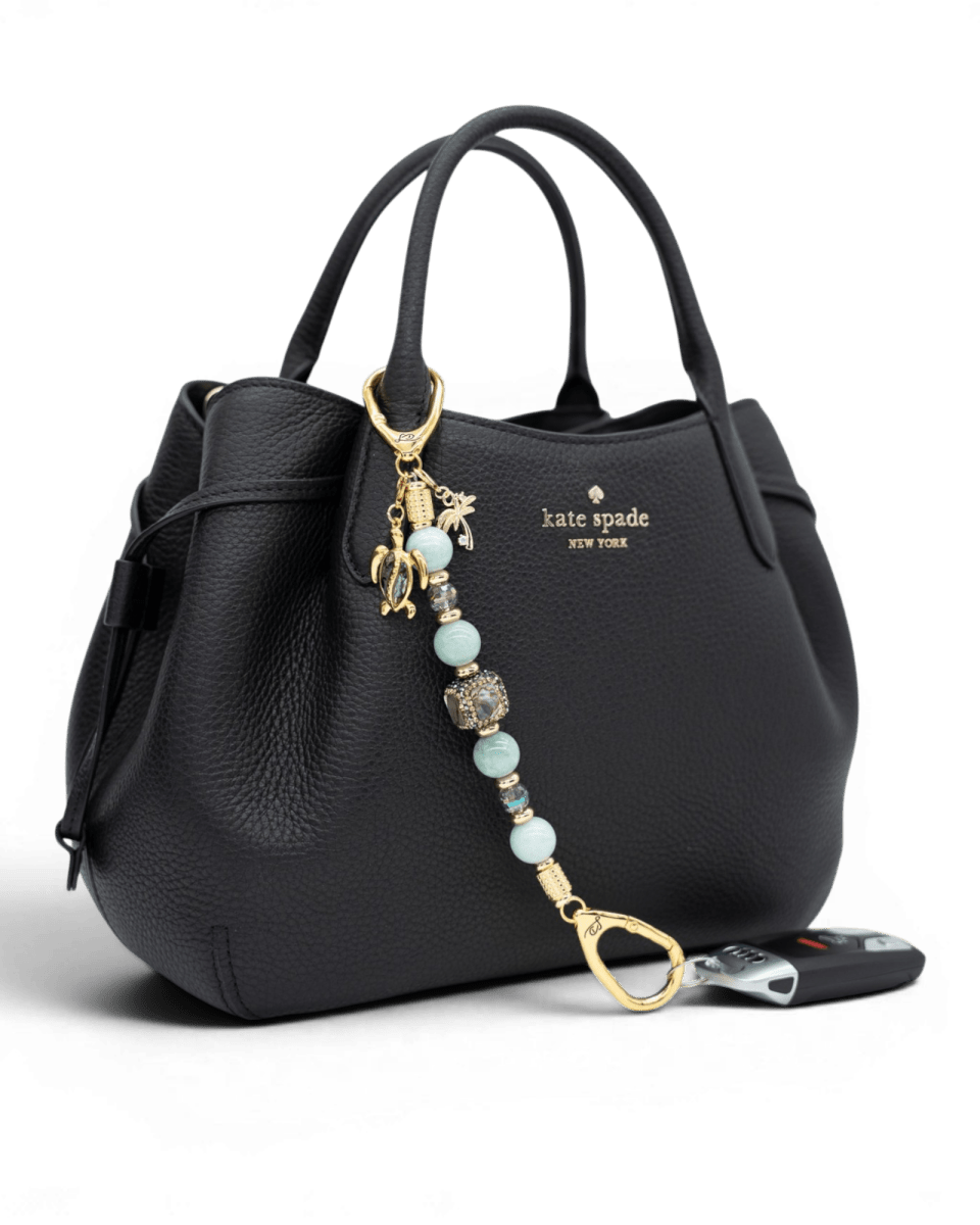 LD Keyfinder Paua Paradise beaded accessory with aqua jade, paua shell, and gold charms attached to a black handbag.