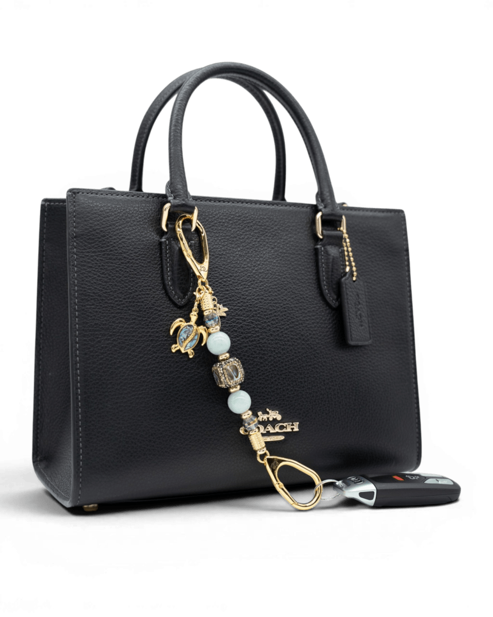 LD Keyfinder Paua Paradise Mini featuring aqua jade beads, paua shell turtle, and palm tree charms on a black bag.