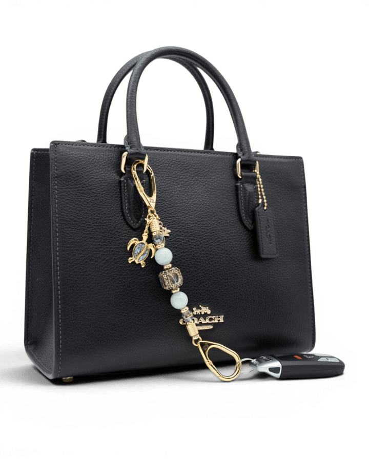 LD Keyfinder Paua Paradise Mini featuring aqua jade beads, paua shell turtle, and palm tree charms on a black bag.