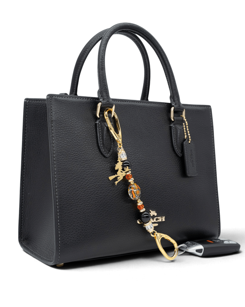 LD Keyfinder Petite Bewitched Halloween charm with black obsidian, orange glass, and gold witch accent on a handbag.
