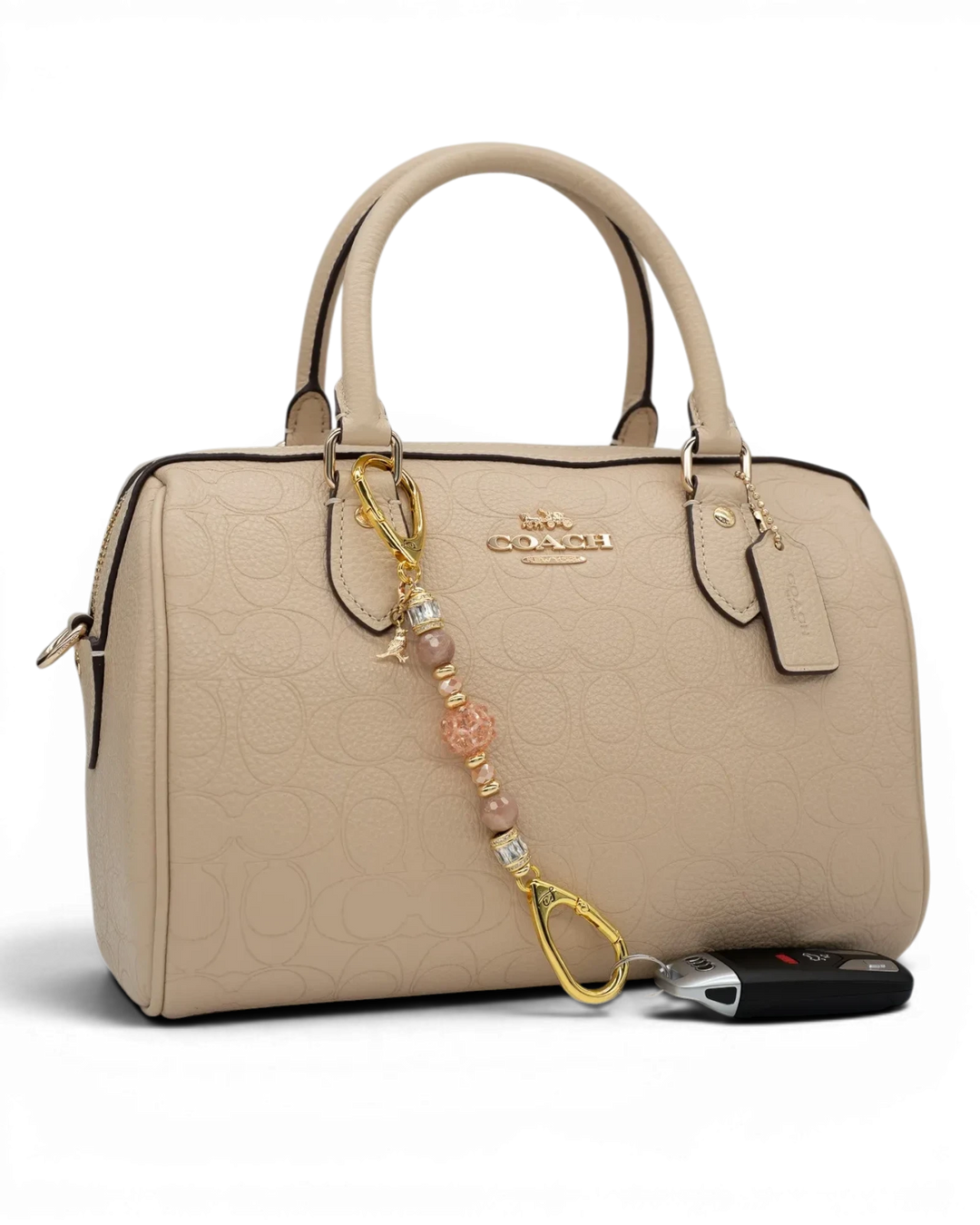 LD Keyfinder Petite Birdsong Bliss beaded charm with sunstone, peach glass, and gold bird accent on a beige handbag.