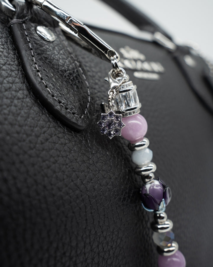 LD Keyfinder Petite Blooming Joy accessory with lavender Lepidolite, purple Jade, and glass tulip on a black handbag