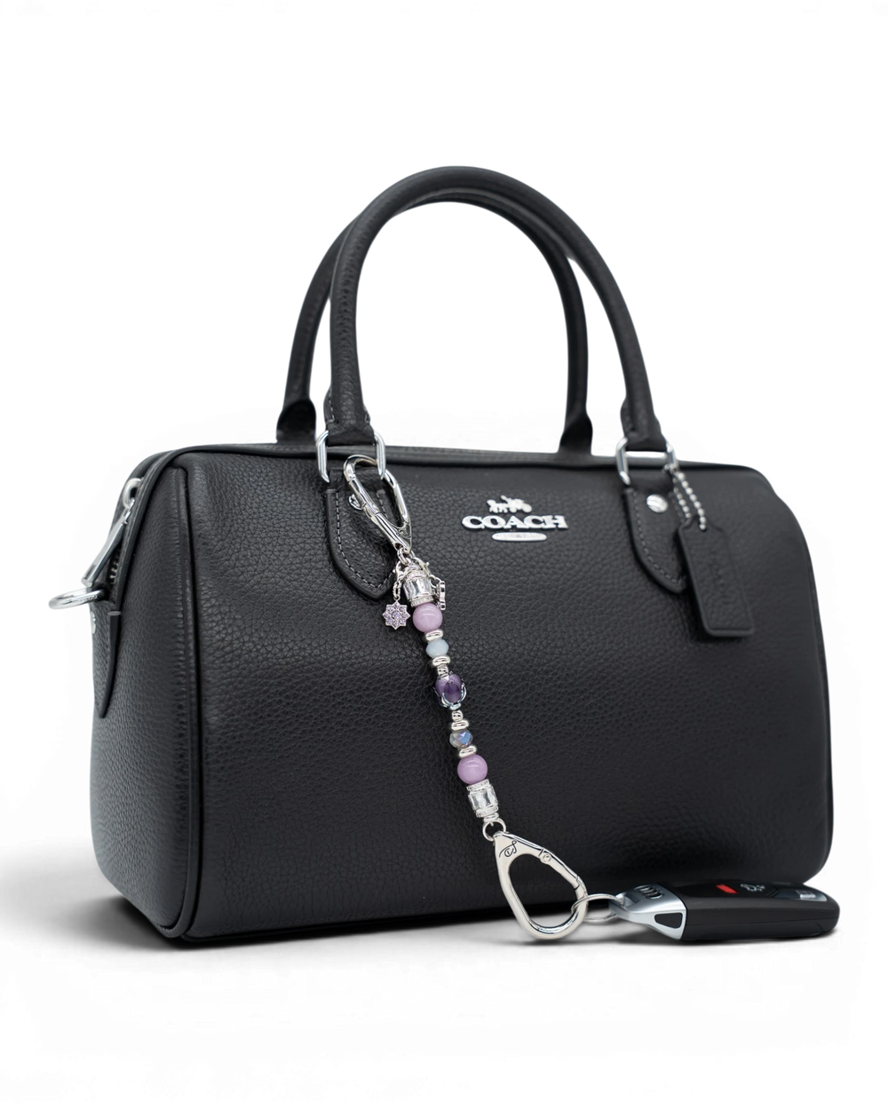 LD Keyfinder Petite Blooming Joy accessory with lavender Lepidolite and purple Jade beads attached to a black handbag.