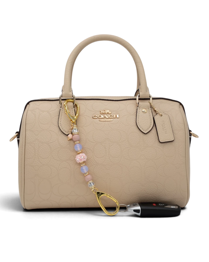 LD Keyfinder Petite Blush Sorbetto beaded accessory with pink opal, opalite, and gold ice cream charm on a beige bag