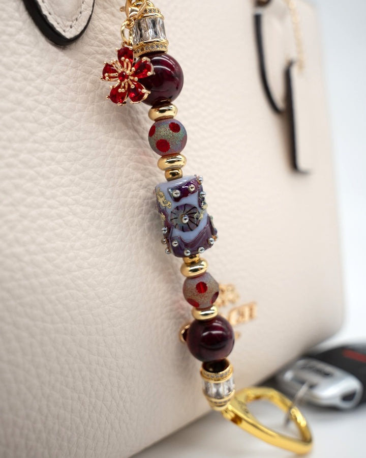 LD Keyfinder Petite Bordeaux Bloom featuring burgundy agate, artisan glass, gold-plated beads, and a red flower charm.
