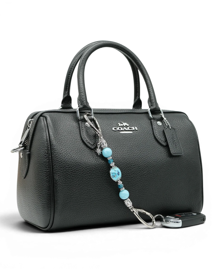 LD Keyfinder Petite Celestial Tide charm with turquoise, aqua, and silver beads, and a star charm, attached to a black handbag.