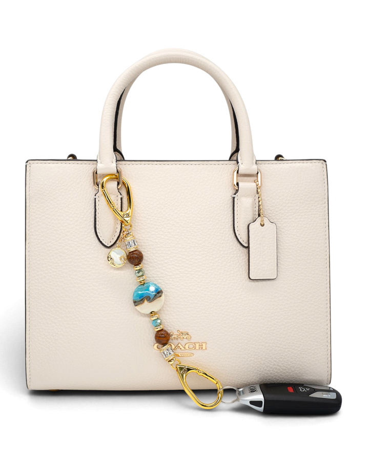 LD Keyfinder Petite Equinox Harmony beaded accessory with artisan glass, jasper, and gold moon charm attached to a handbag