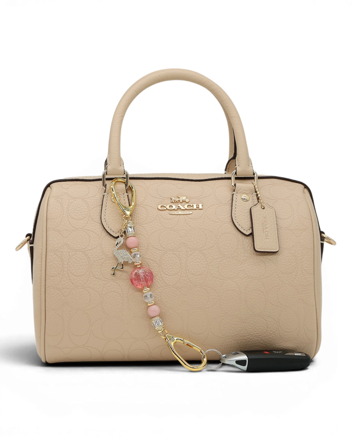 LD Keyfinder Petite Flamingo Fantasy accessory with pink opal beads and gold flamingo charm on a beige handbag