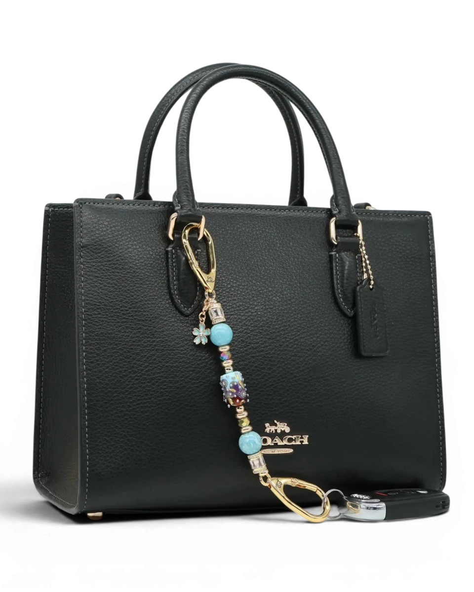 LD Keyfinder Petite Gilded Fantasy keychain with blue glass bead, gold leaf, larimar, and flower charm on black bag.