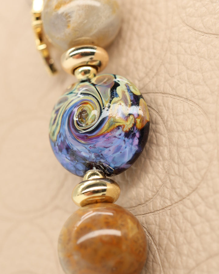 LD Keyfinder Petite Golden Nebula artisan glass bead with purple and gold swirls, fossil coral beads, gold spacers, and rhinestone charm.