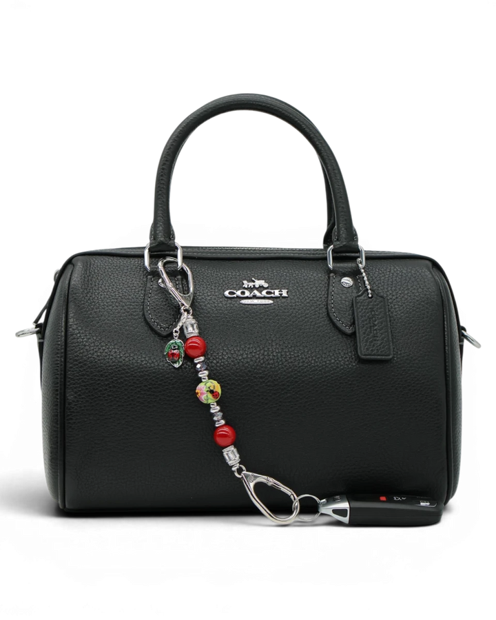 LD Keyfinder Petite Ladybug Love accessory with red shell pearls and artisan glass bead attached to a black handbag.