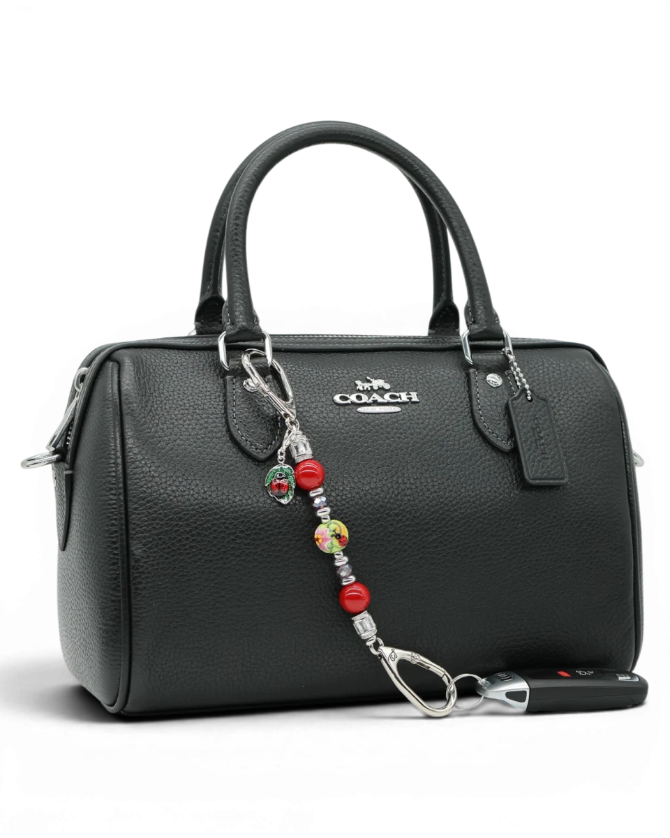 LD Keyfinder Petite Ladybug Love accessory with red shell pearls, artisan glass bead, and ladybug charm on a handbag.