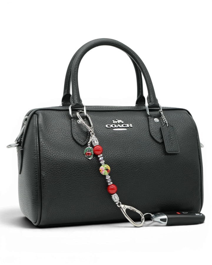 LD Keyfinder Petite Ladybug Love accessory with red shell pearls, artisan glass bead, and ladybug charm on a handbag.