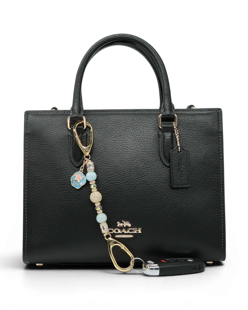 LD Keyfinder Petite Pastel Garden charm with aquamarine, pink glass beads, and gold-plated details on a black handbag.