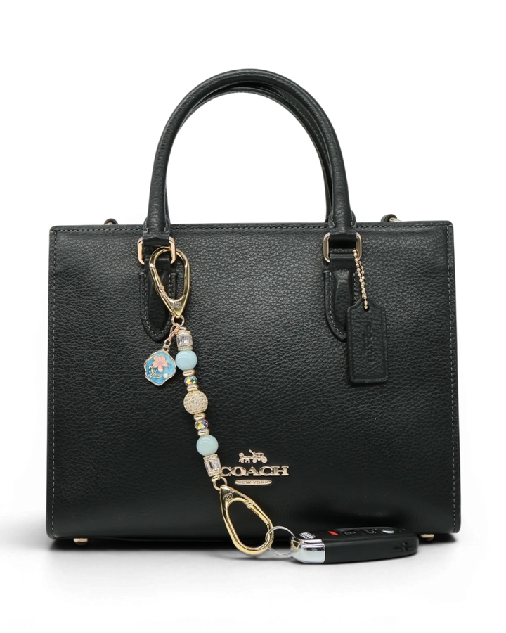 LD Keyfinder Petite Pastel Garden charm with aquamarine, pink glass beads, and gold-plated details on a black handbag.