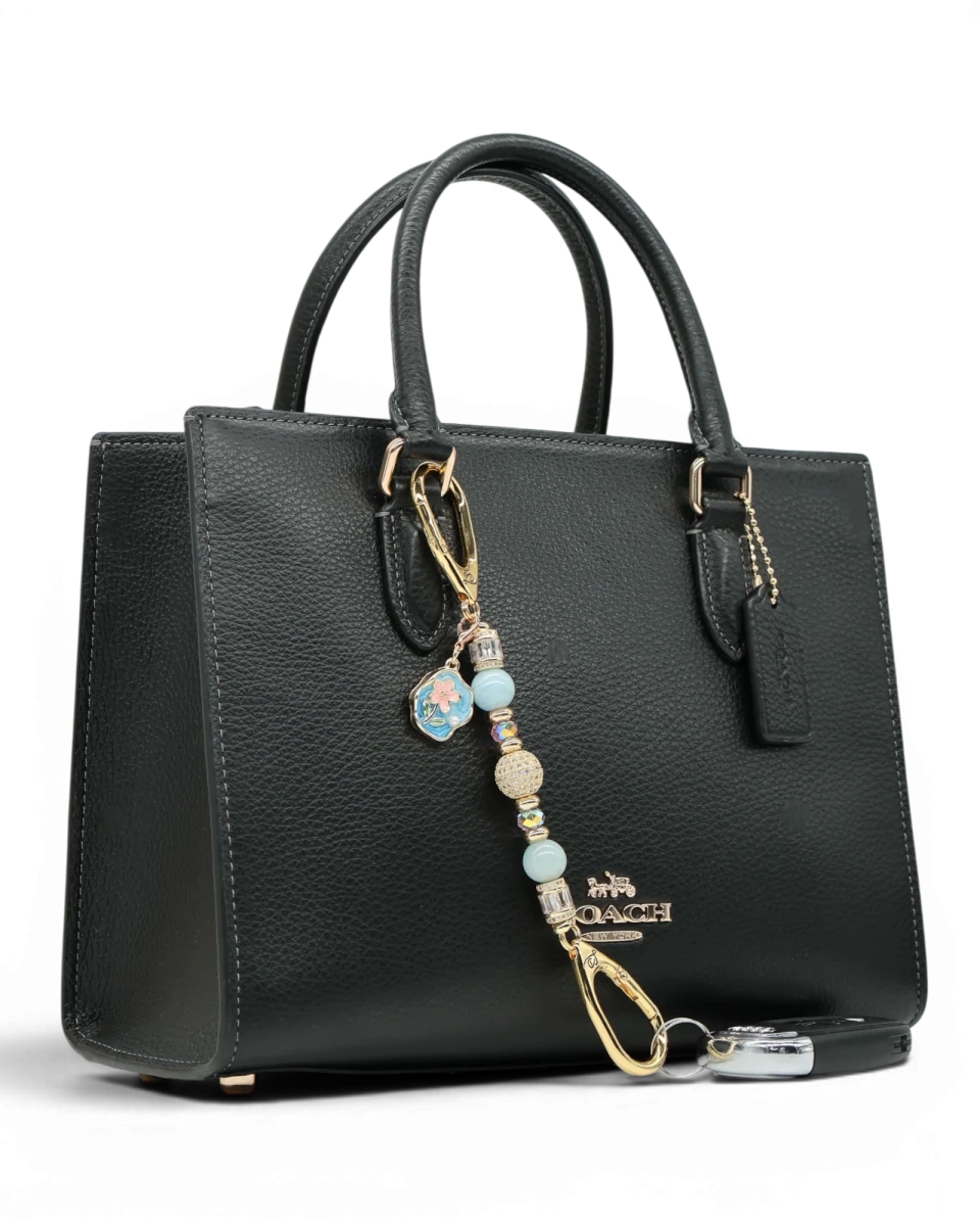 LD Keyfinder Petite Pastel Garden charm with aquamarine, pink glass beads, and gold-plated flower charm on a black handbag.